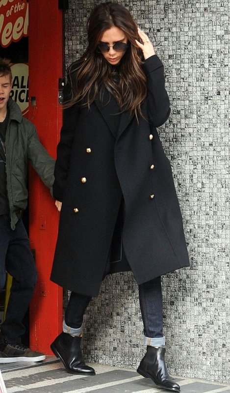 Виктория Бекхэм в сапогах и черном пальто в стиле милитари